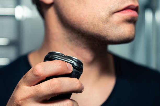 Man preparing to shave stubble with a black electric foil shaver.
