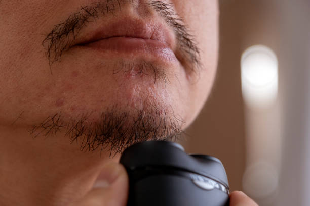 Man shaving stubble from his chin with a foil shaver.